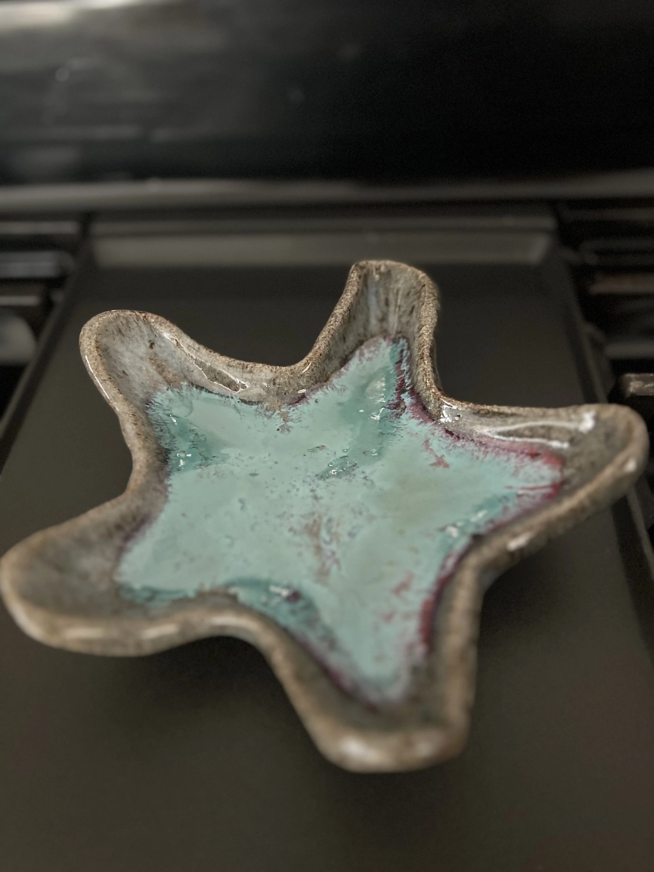Star-shaped ceramic dish with a glazed turquoise interior and a rustic design.