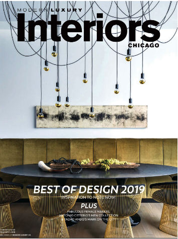 Cover of a magazine titled "Luxury Interiors Chicago" featuring a modern dining room with a large table, green upholstered bench, black chairs, and contemporary hanging light fixtures.