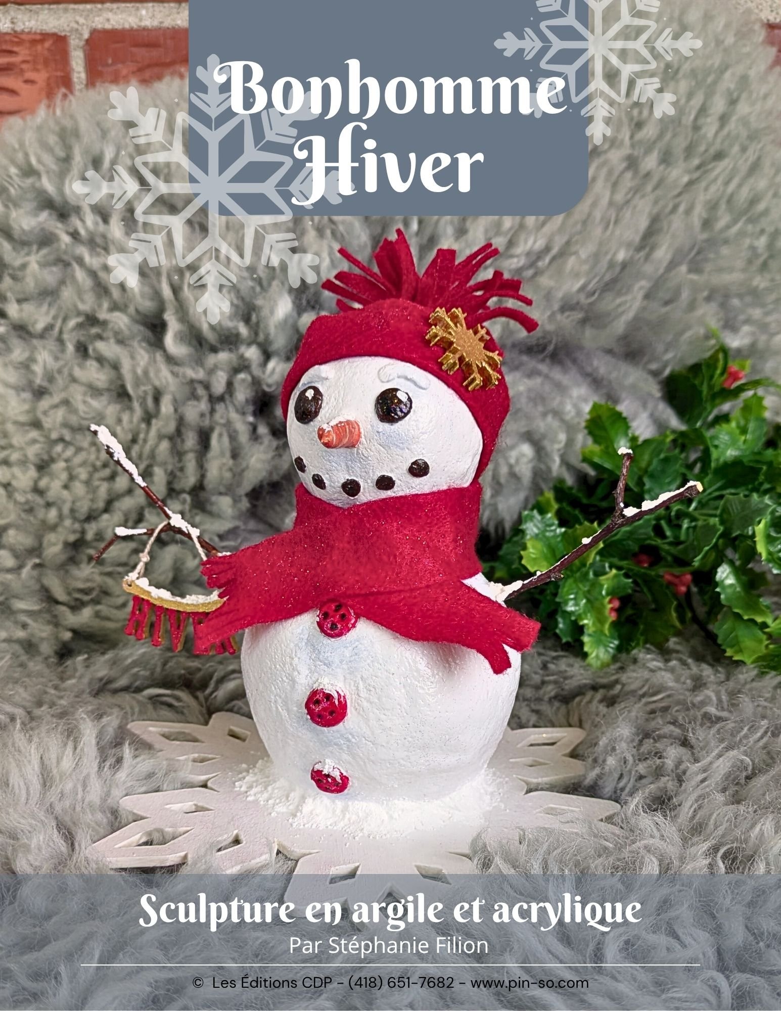 Sculpture de bonhomme de neige en argile et acrylique portant un bonnet rouge et une écharpe rouge, avec des boutons rouges en haut de son corps et une carotte pour le nez, entourée de branches, de houx et d'une texture de fond de laine grise.