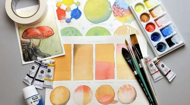Matériel de peinture comprenant des tubes de peinture, des pinceaux, une palette avec des couleurs, des cartes de référence pour les couleurs, et une peinture aquarelle représentant des champignons rouges, établi pour peindre ou créer de l'art.