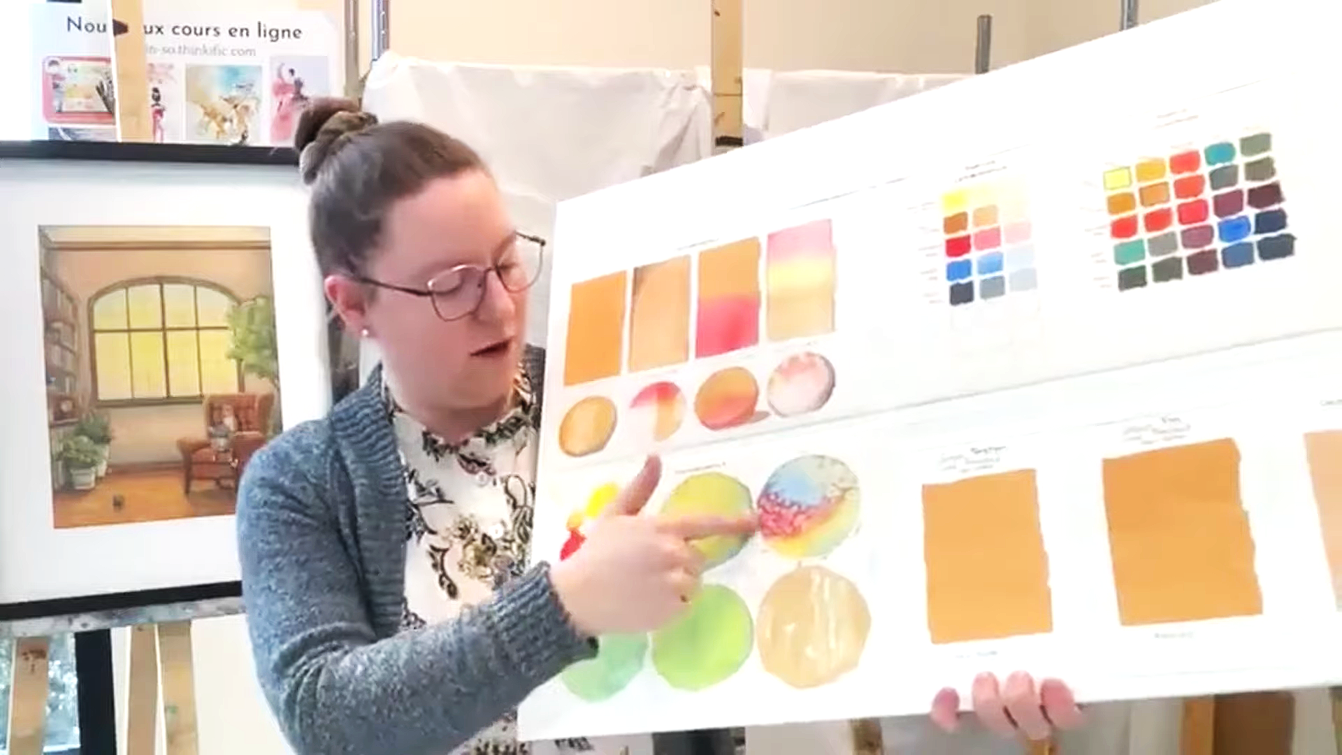 Femme expliquant une affiche colorée contenant des échantillons de couleurs et des diagrams illustrant différents dégradés et palettes de couleurs.