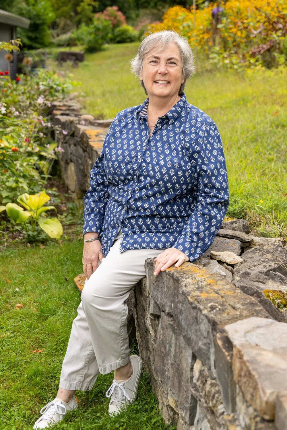 Elizabeth Maffey smiling leaning against stone wall