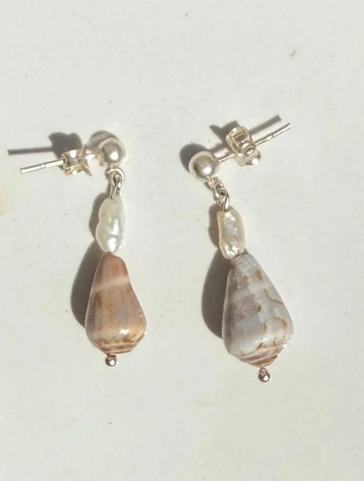 Silver earrings with pearls and teardrop-shaped shells hanging from them.