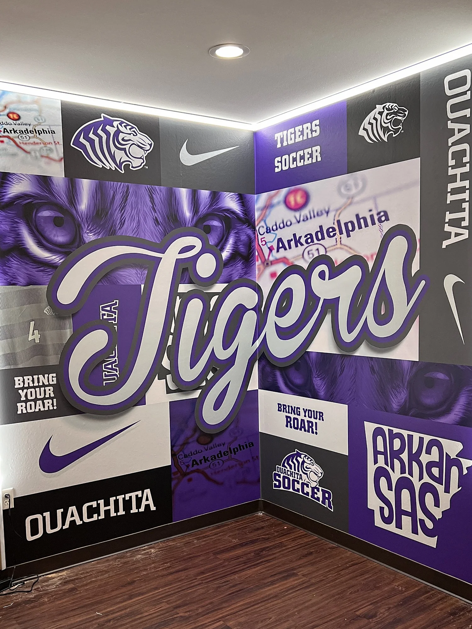 Custom corner wall wrap for Ouachita Baptist University Women’s Soccer featuring purple and silver graphics, layered typography, and perimeter LED lighting.