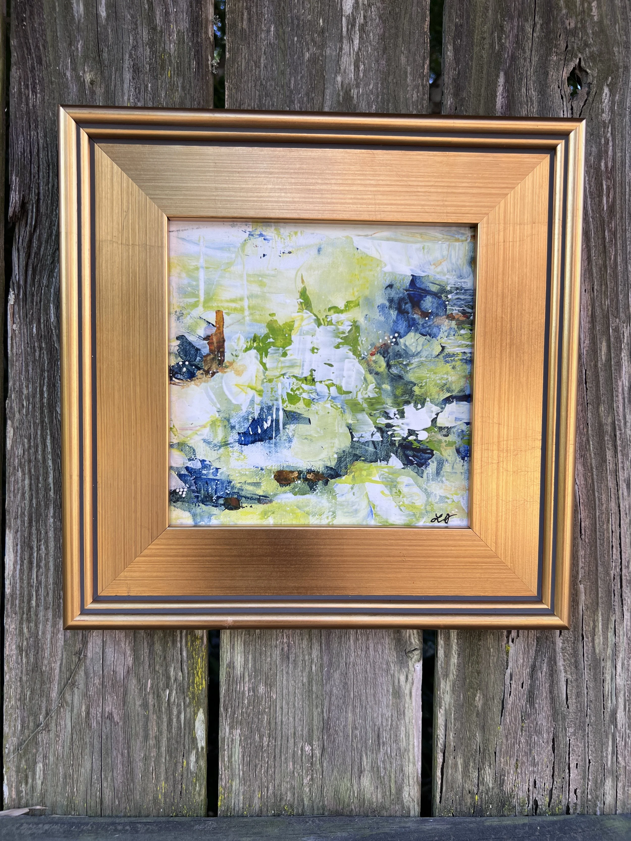 Small framed abstract with lively greens, blues, whites, and sienna accents in an 8×8 acrylic painting with gold frame.