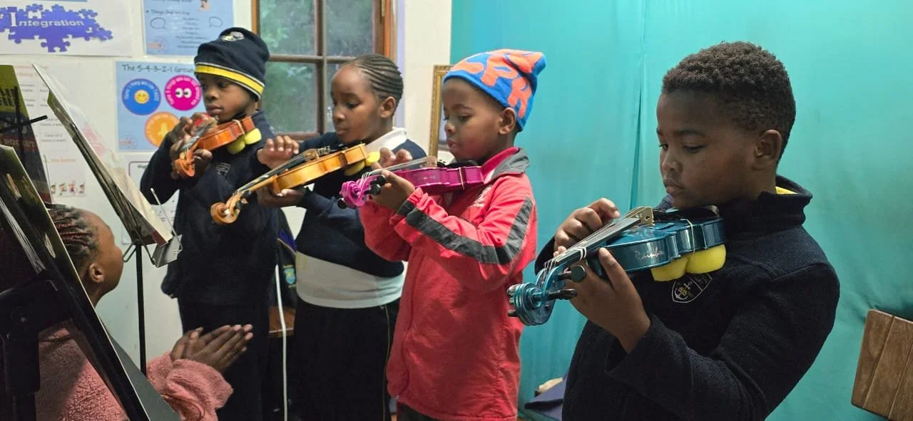 Vier Kinder spielen zusammen Geige. Sie sind am lernen.