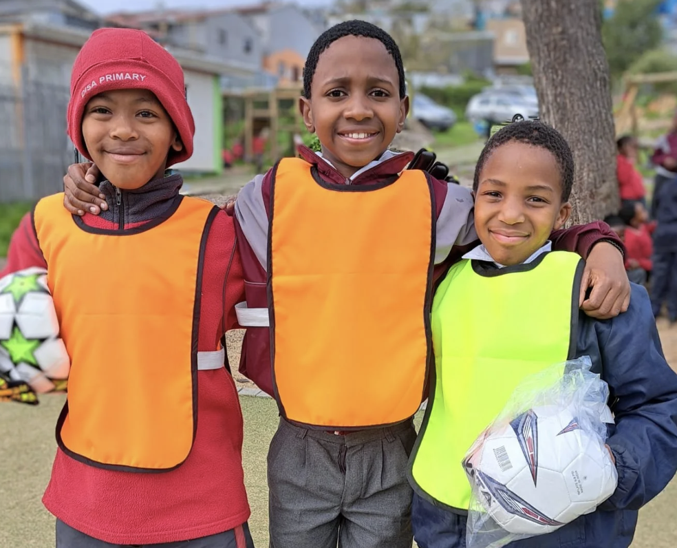 Drei Jungs posieren und lachen mit ihrem Fussball in der Hand.