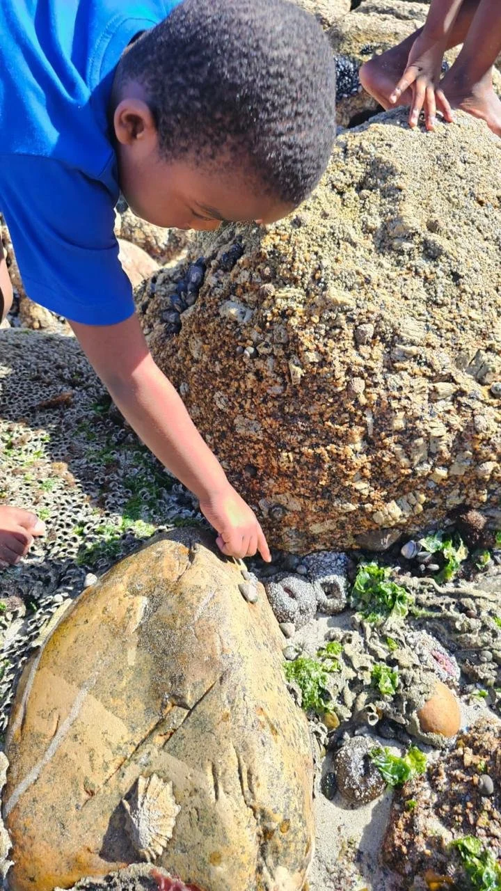 Ein Junge vom Kindergarten Little Lambs in Kapstadt spielt am Strand.