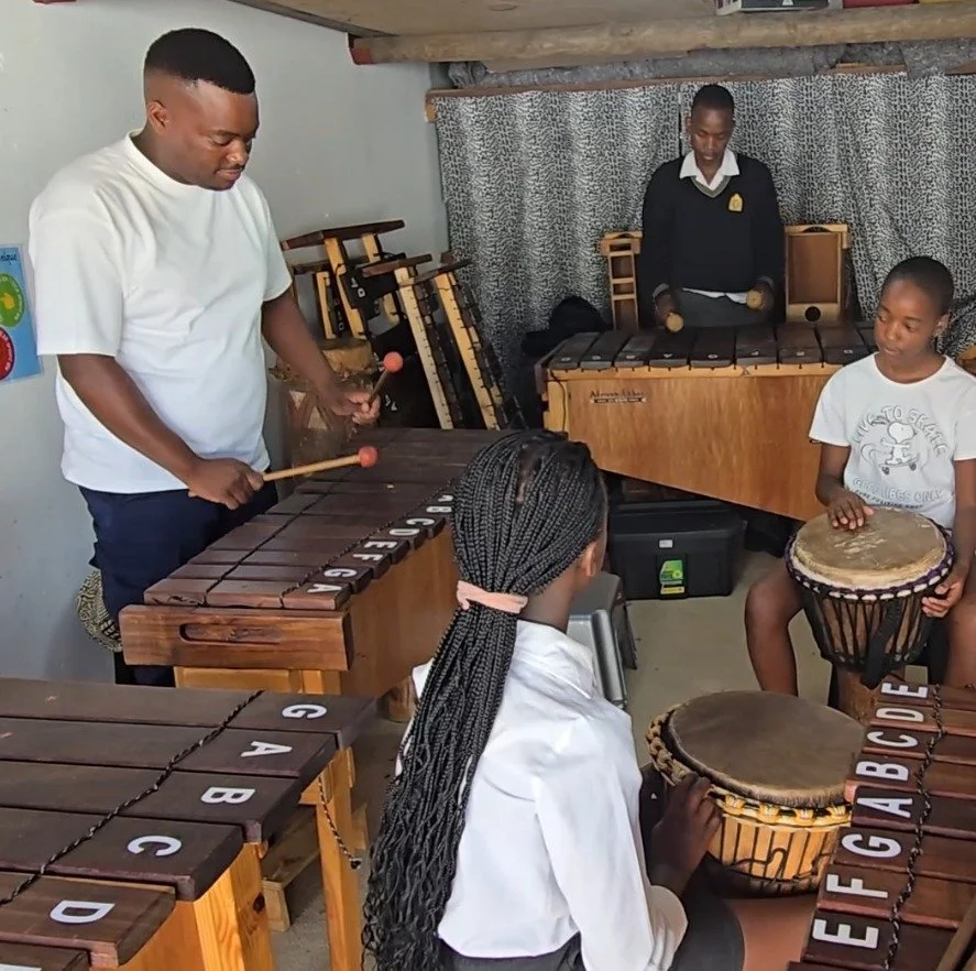 Die Schülerinnen und Schüler spielen mit ihrem Lehrer Xyolphon und Trommel an der Kronendal Music Academy.