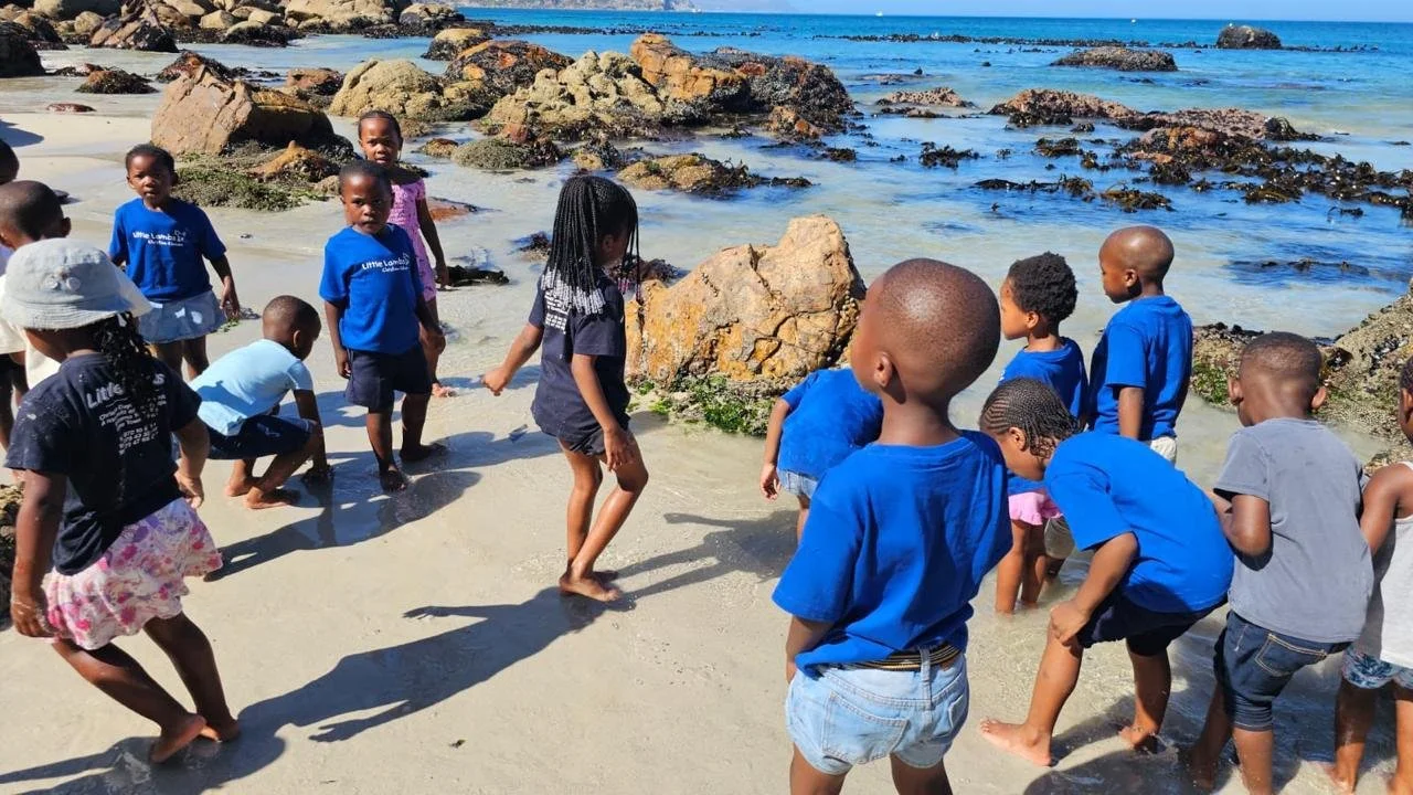 Kinder vom Kindergarten Little Lambs in Kapstadt spielen gemeinsam am Strand.