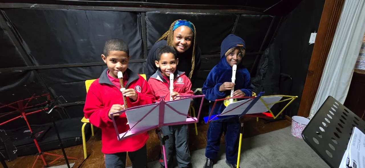 Drei Kinder lernen mit ihrer Lehrerin Blockflöte und sie haben Spass.