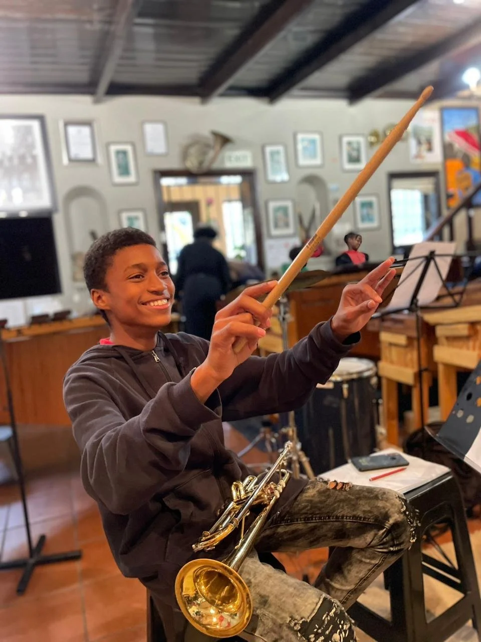 Ein Junge lacht und dirigiert mit seinen Schlagzeug-Schlägern.