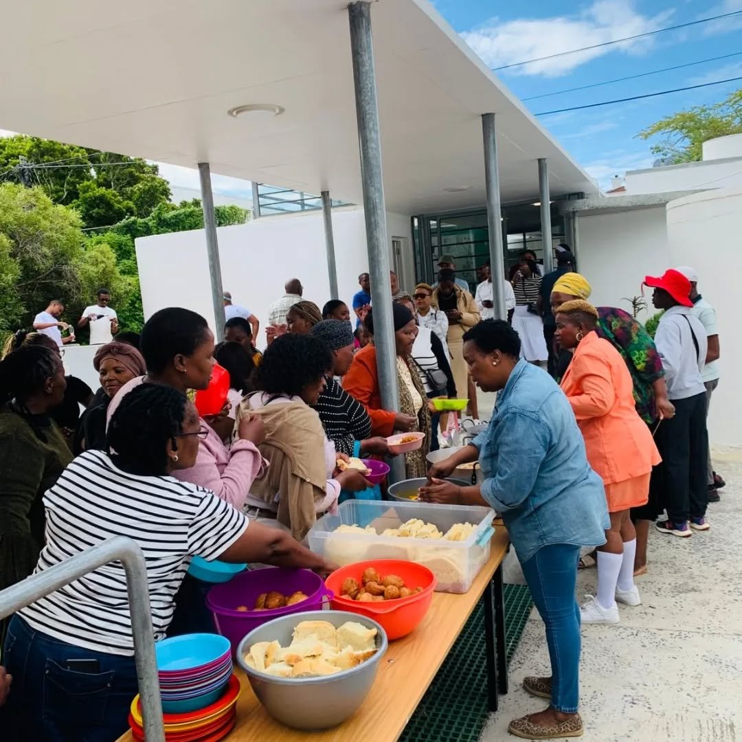 Leherinnen stehen an einem Buffet und schöpfen Essen für die Community, organisiert von Sakhisizwe.
