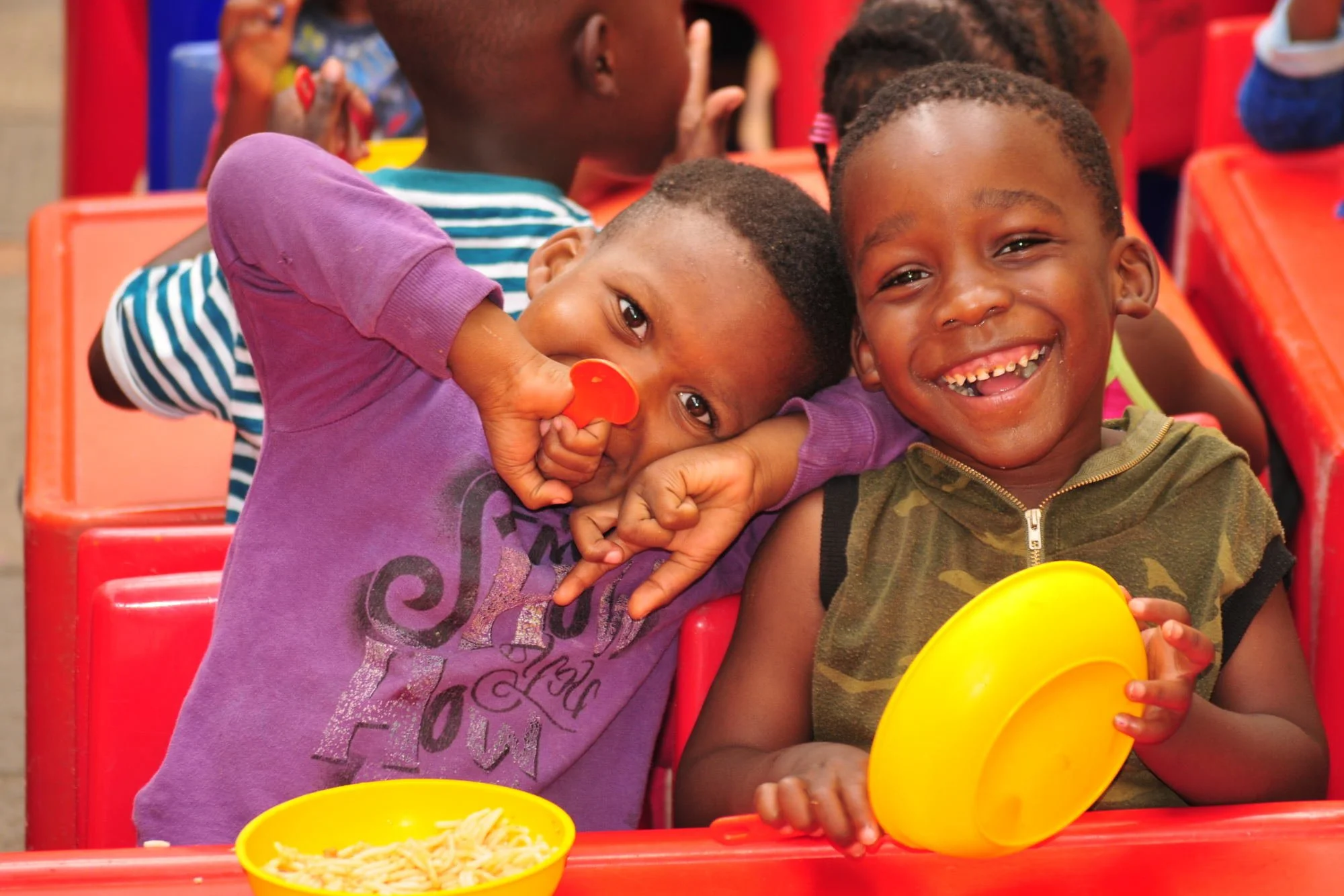 Zwei Jungs lachen und essen im Kindergarten iKhaya le Themba.