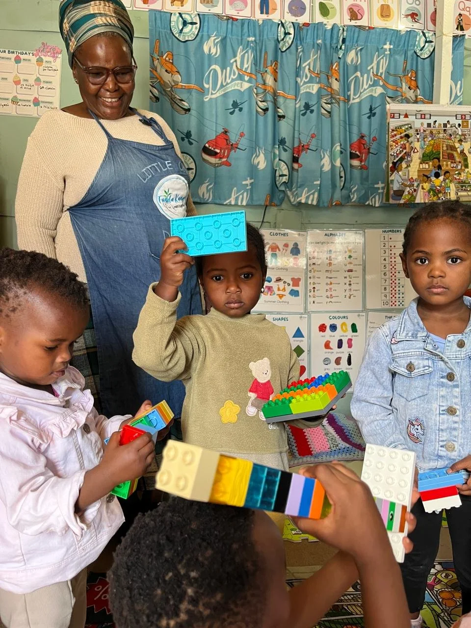 Die Lehrerin beaufsichtigt Kinder beim spielen mit Lego.