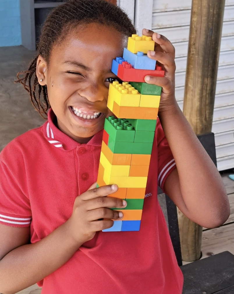 Mädchen lacht und spielt mit Lego.