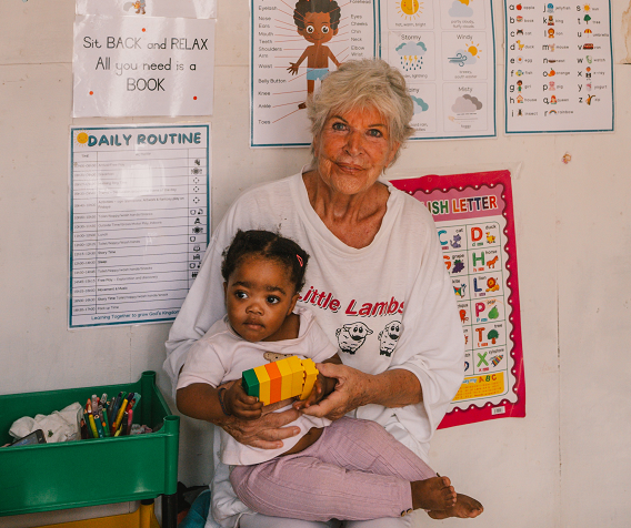 Marlis Schaper sitzt mit einem Mädchen in einem Klassenzimmer von Funda Kunye.