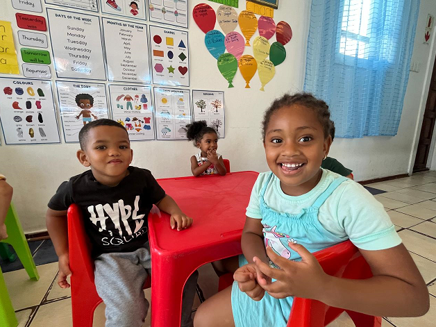 Lachende Kinder sitzen an einem Tisch im Klassenzimmer von Funda Kunye.