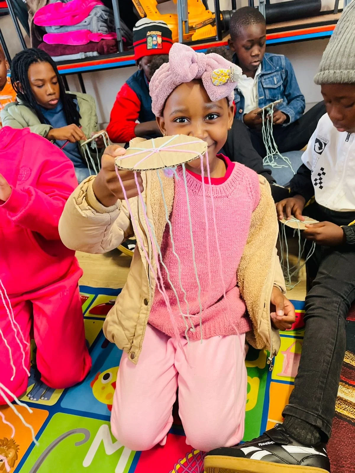 Ein Mädchen im Imizamo Yethu Learning Hub in Kapstadt zeigt ihre Bastelarbeiten.