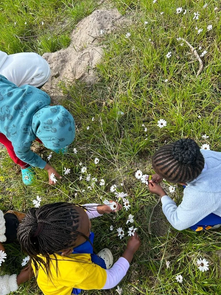 Kinder von True North pfücken Blumen auf einer Blumenwiese.