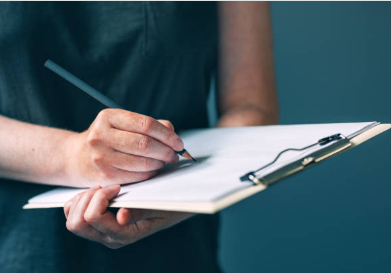 Person taking notes on a clipboard with a pen.