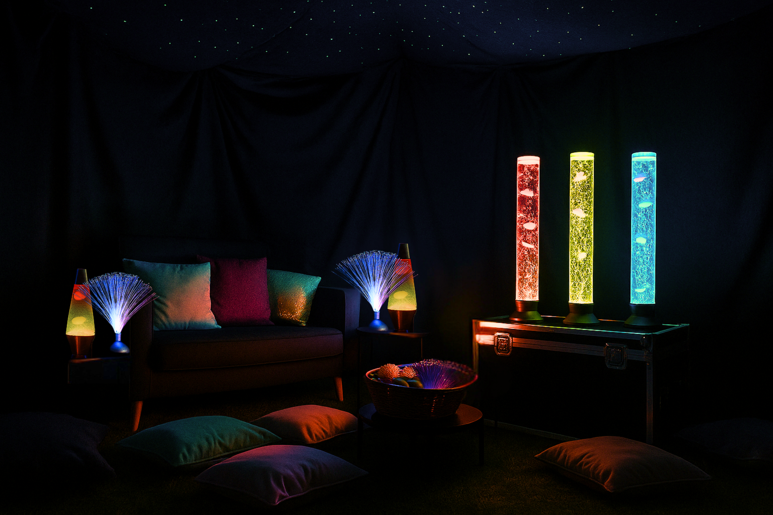An inviting cozy and dark room decorated with colorful LED lights, including pillows on the floor, a small sofa, lava lamps, and bubble tubes emitting vibrant colours. Inclusive sensory space by Bass Therapy featuring calm lighting, soft furnishings.