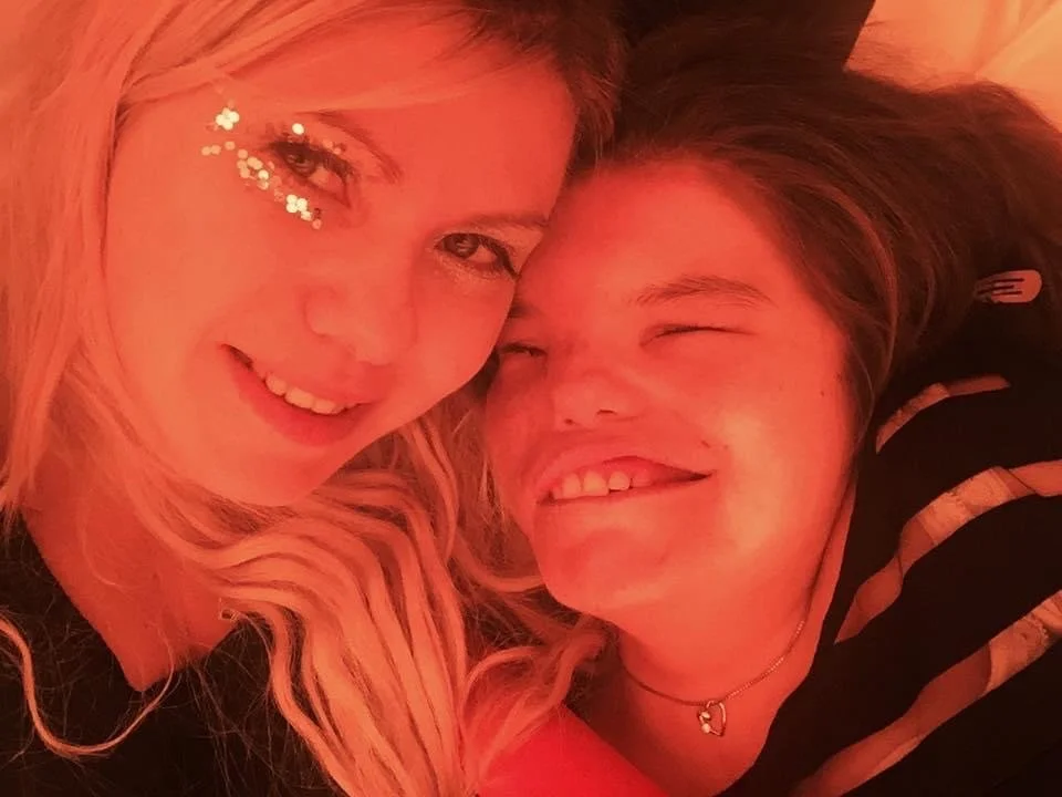 Two young women smiling, close-up selfie, warm lighting, one has star-shaped face glitter. This is Kyley and Jody, the founder and reason behind J-Fest.