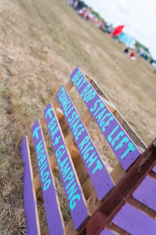 Colourful  signs on a wooden bench with directions for different seating areas at J-Fest including different stages.