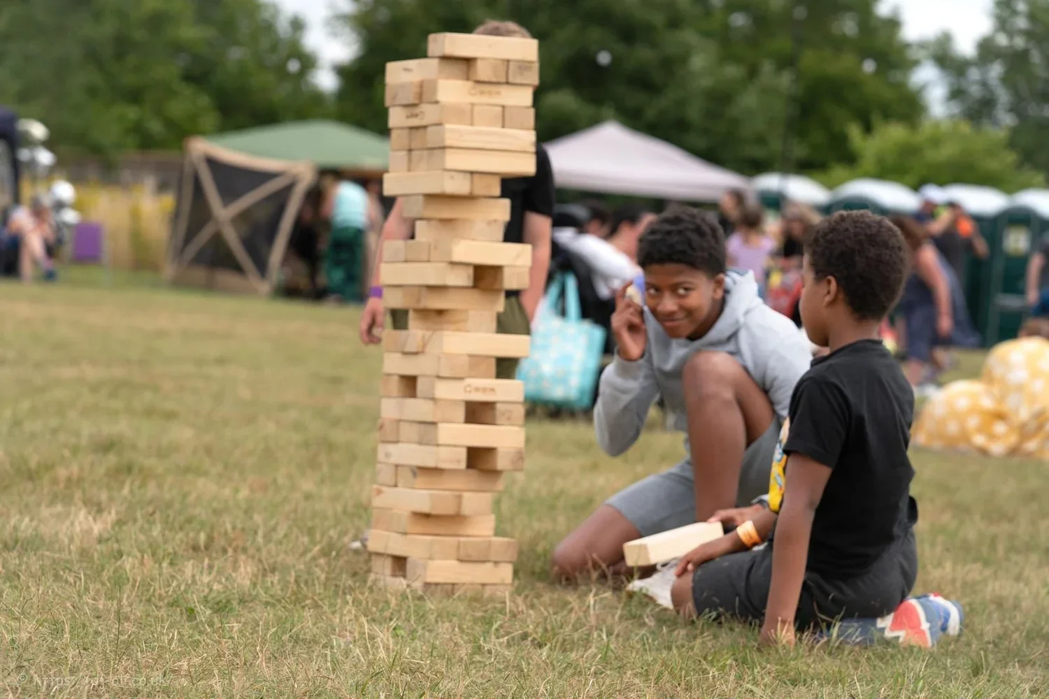 Two boys playing giant Jenga outdoors at J-FEST.