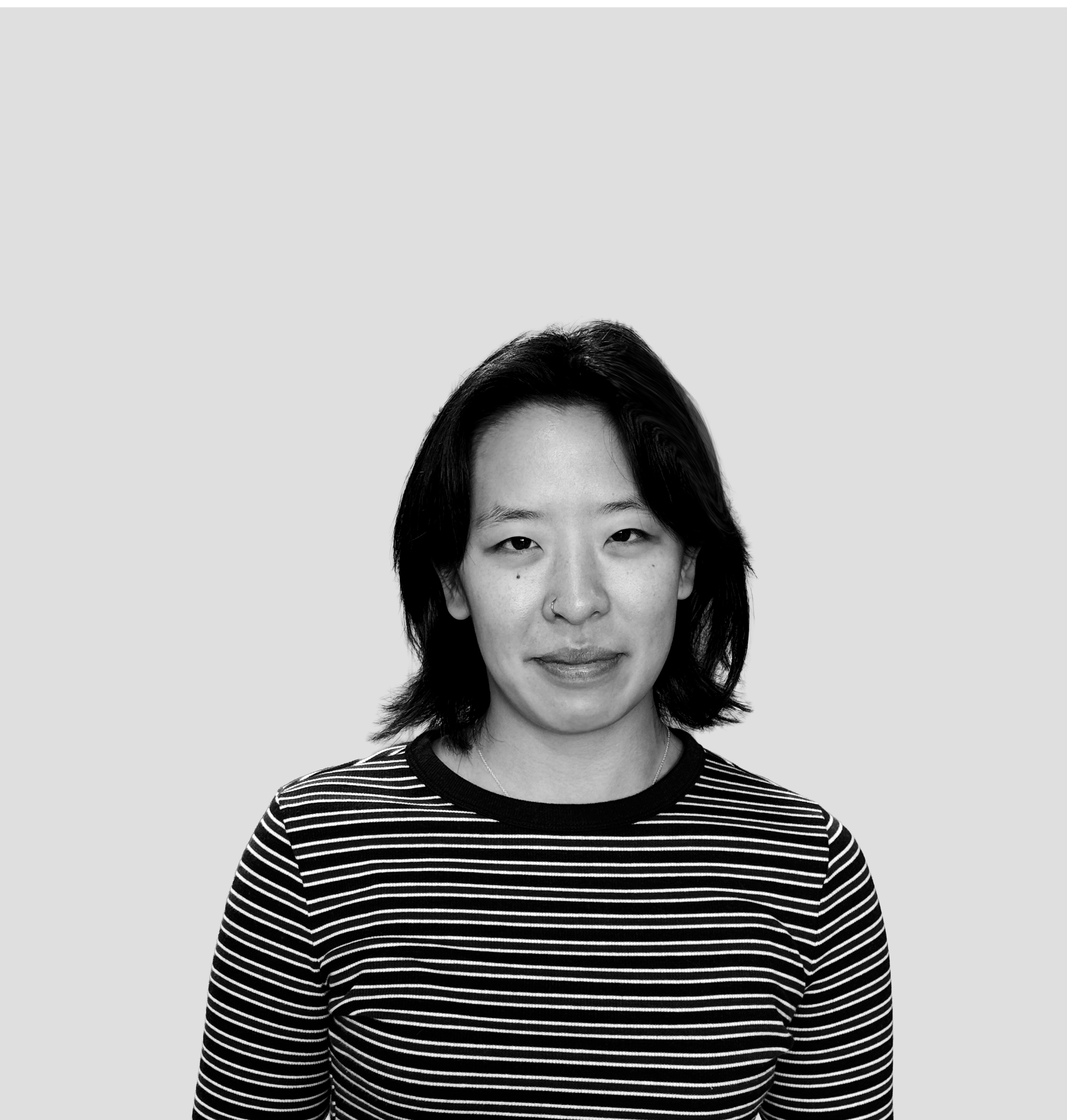 Black and white portrait of a woman with shoulder-length dark hair, wearing a striped shirt, smiling slightly, against a plain light background.