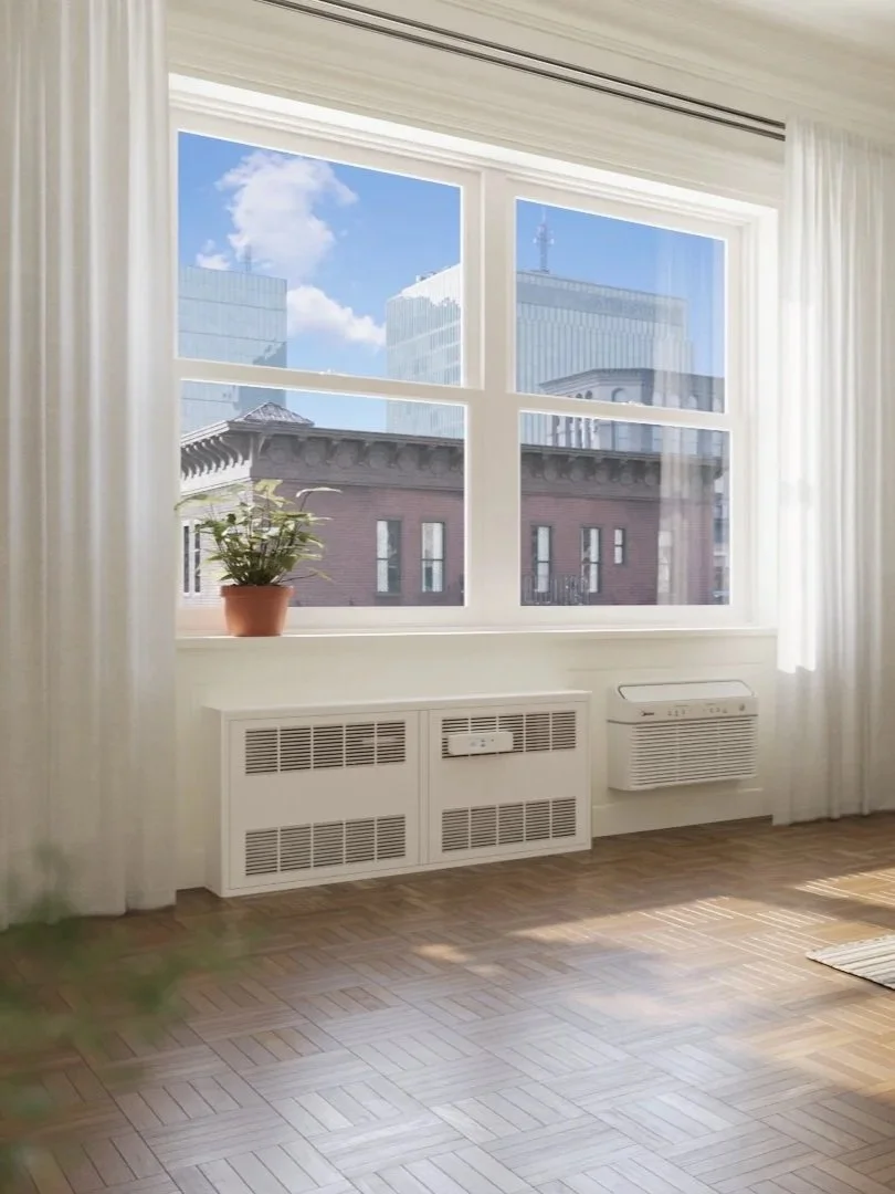 Sun lit room, zoomed into the window. There is a recessed convector radiator and a heat pump below the window.