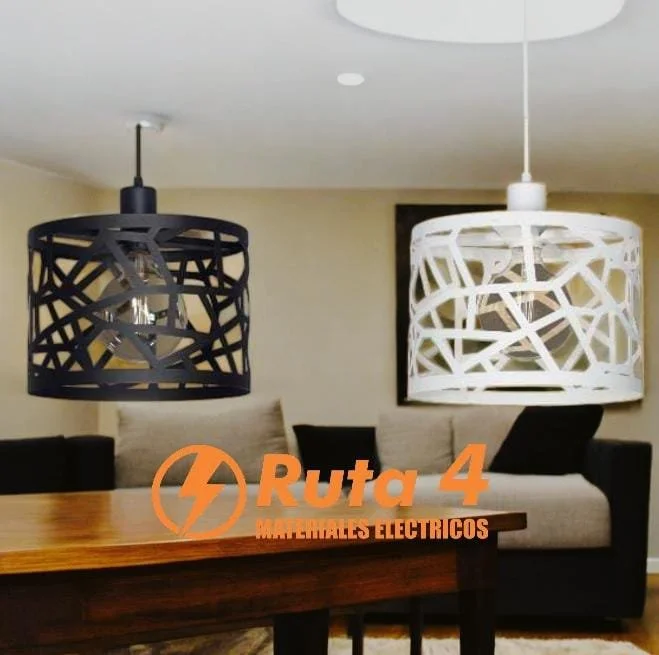 Dos lámparas colgantes modernistas, una negra y otra blanca, sobre una mesa de madera en una sala con sofá beige y cojines negros.