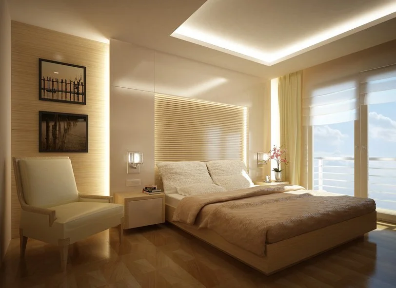 Habitación moderna y elegante con cama grande, sillón blanco, ventanas grandes con vista al mar, y decoración en tonos neutros.