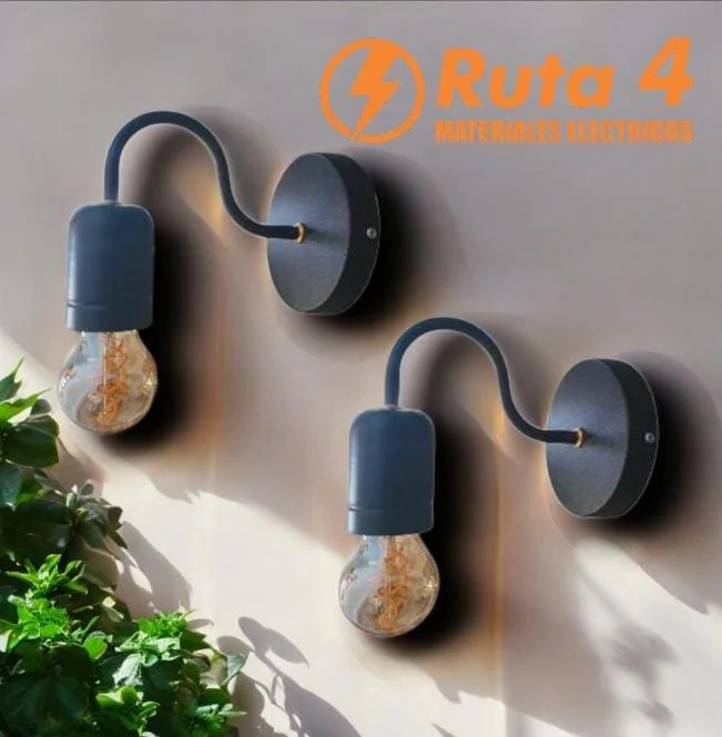 Un par de apliques de pared en forma de bombilla, conectados a una pared de color gris, con una planta verde en la esquina inferior izquierda y un logotipo naranja en la parte superior derecha que dice "Ruta 4 Materiales Eléctricos".