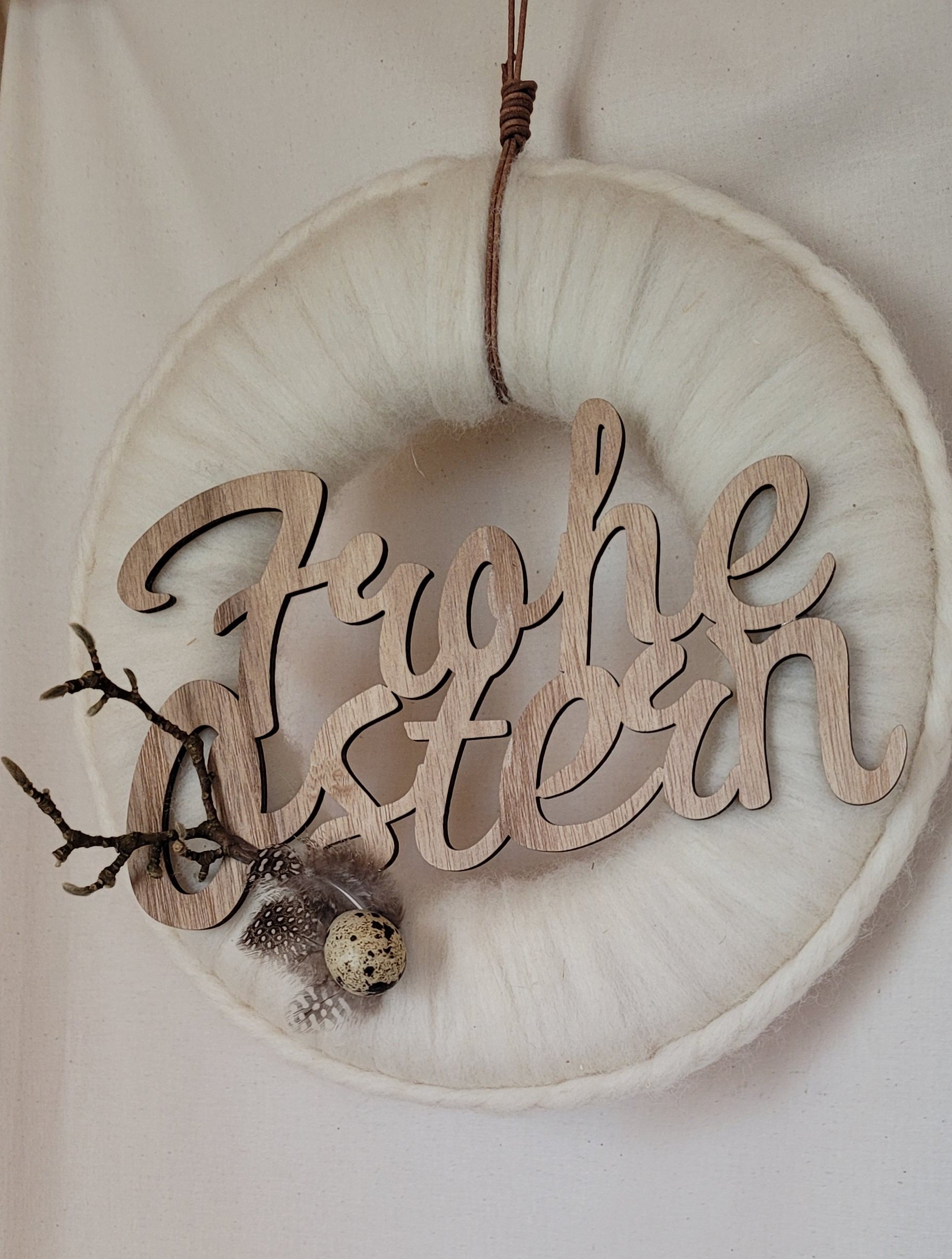 mit Wolle umwickelter Holzkranz dekoriert mit Holzschriftzug