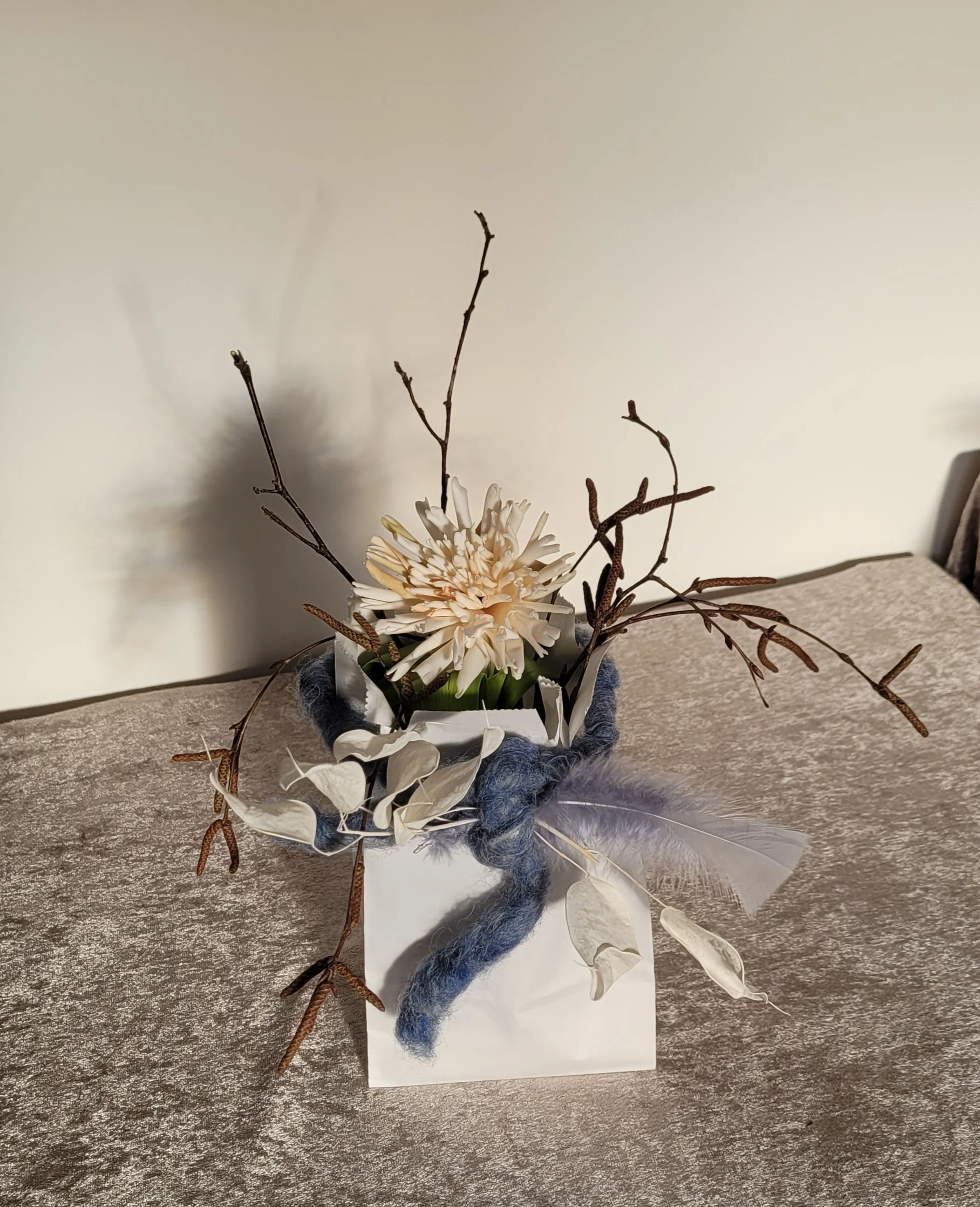 künstliche Dahlie mit Birkenzweigen arrangiert in Papiertüte