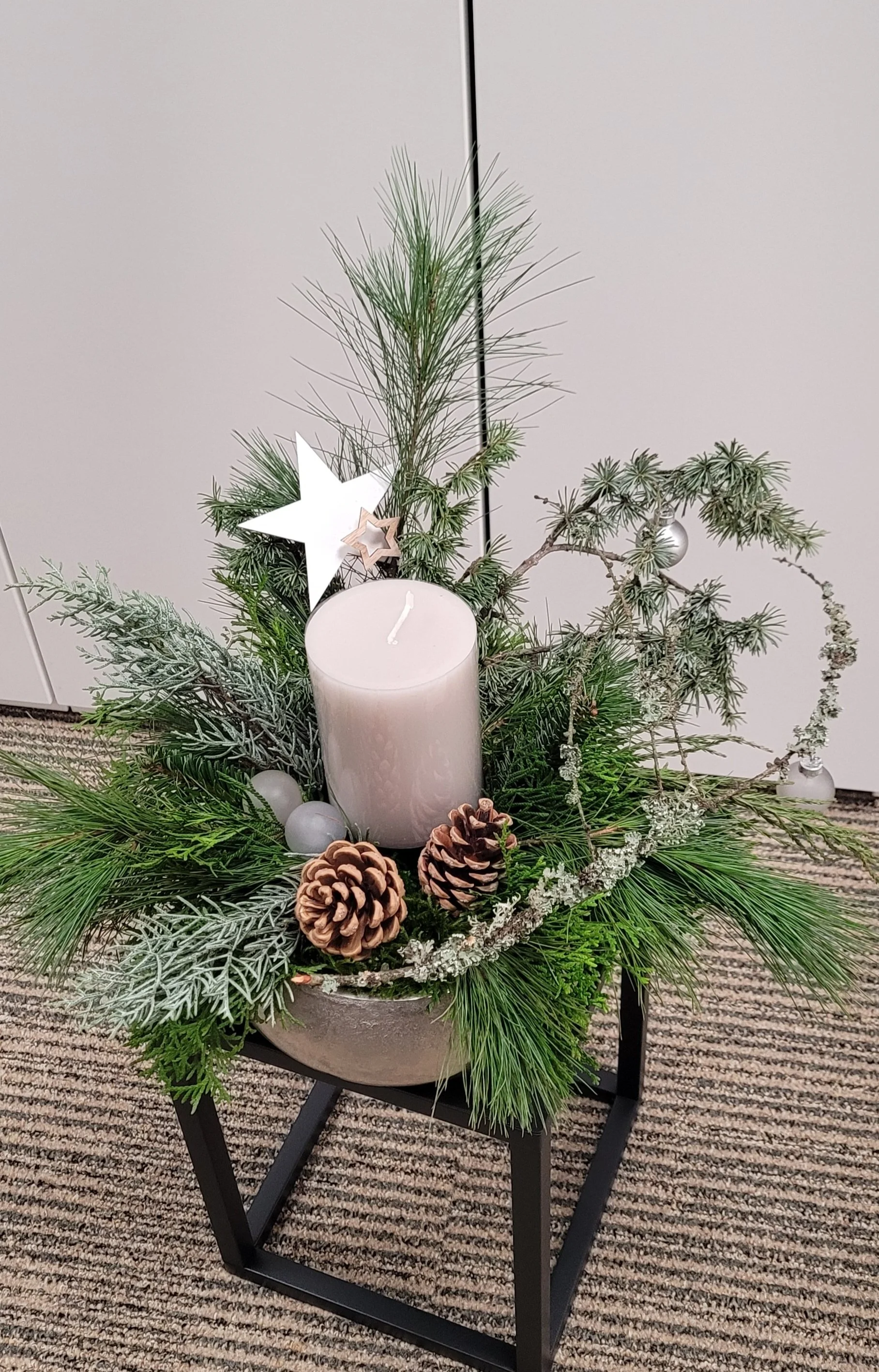 edle, durchgefärbte echte Kerze arrangiert mit verschiedenen Naturzweigen im Metallgefäß