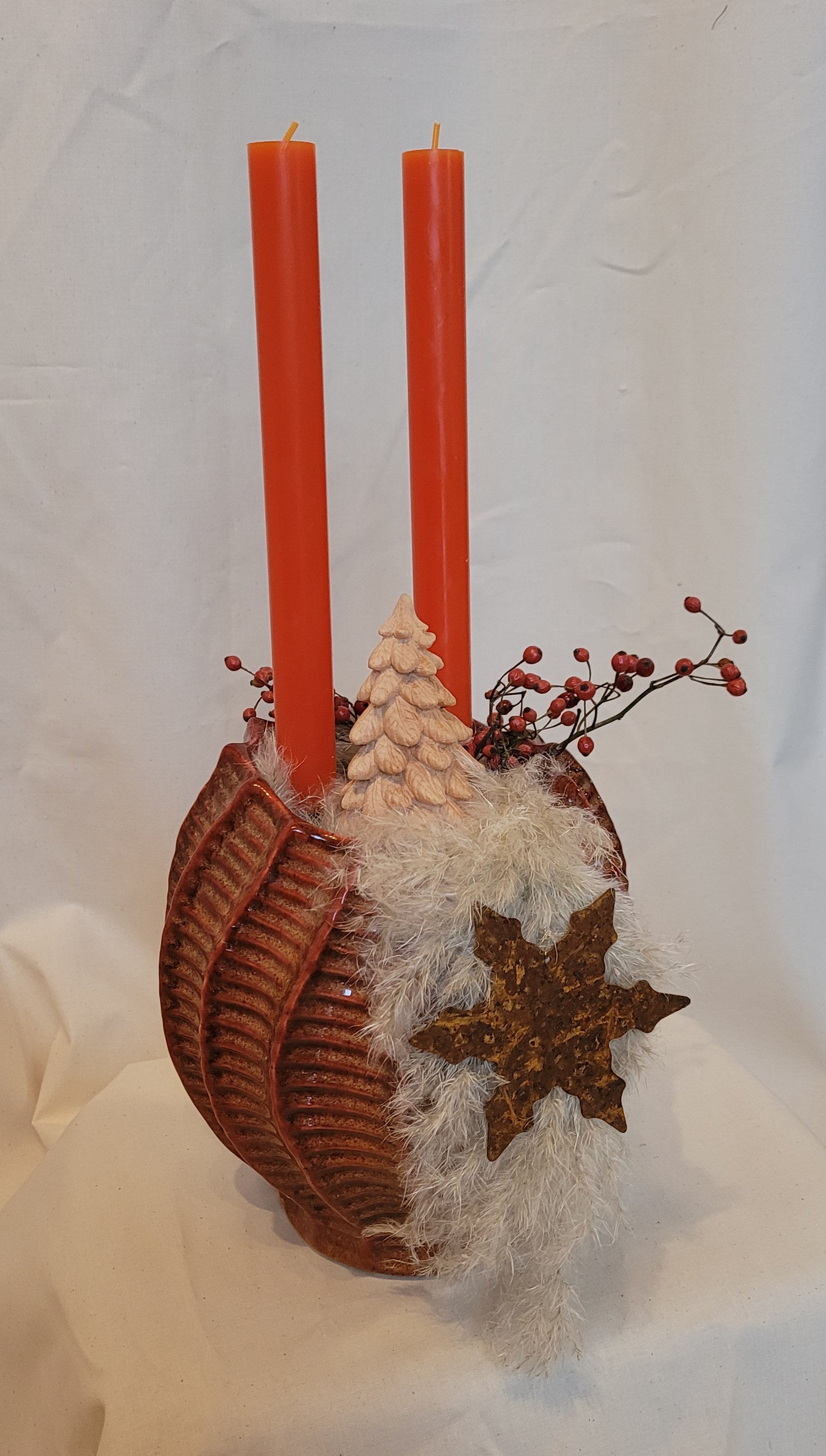 edle, durchgefärbte Echtwachs-Stabkerzen gesteckt in einer hochwertigen Keramikvase, dekoriert mit einer handgeschnitzten Zirbenholztanne