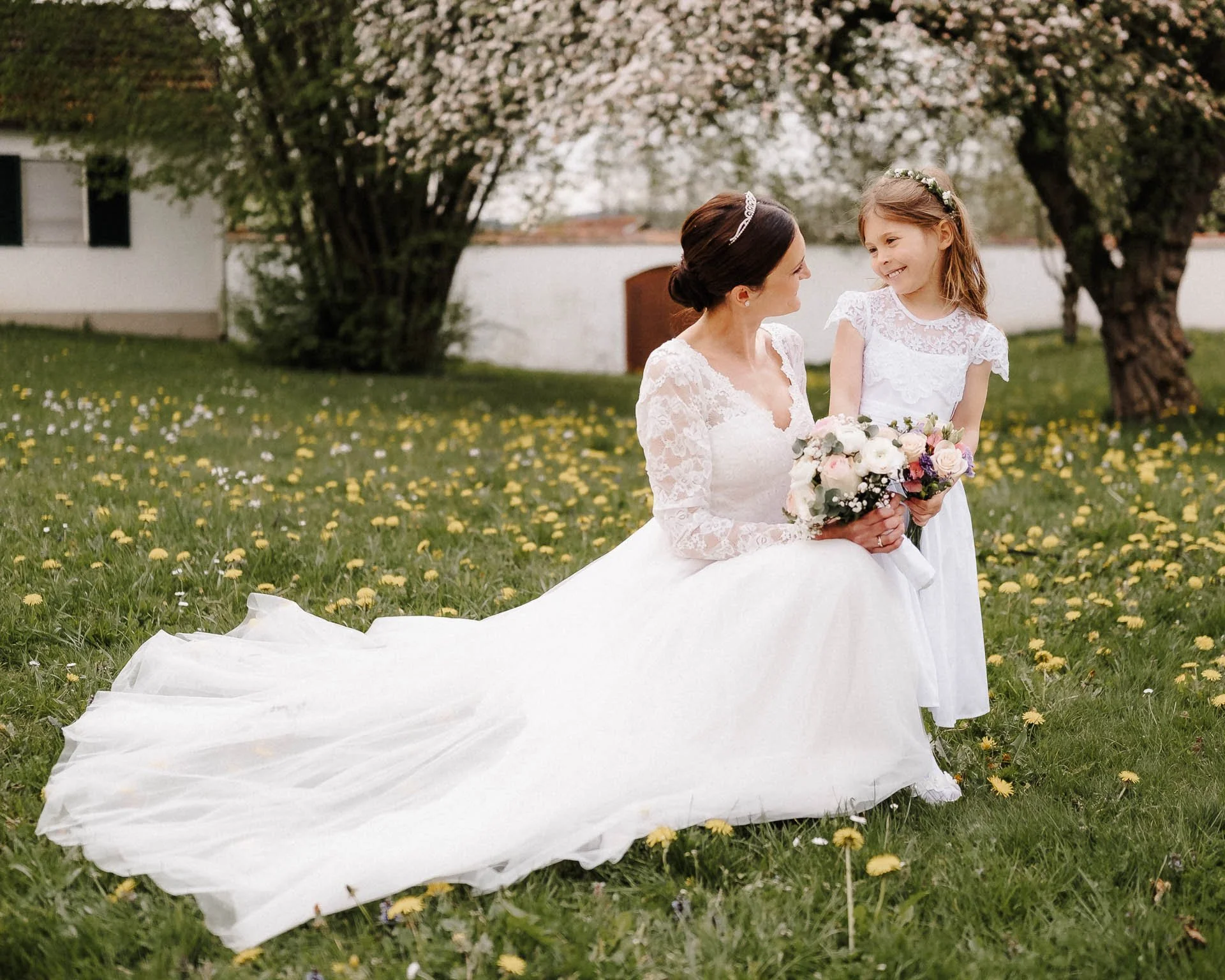 Eine Braut und ihre Tochter in weißen Kleidern schauen sich beim Fotoshooting nach der Trauung in der Region Stauden bei Augsburg  emotional und voller Liebe in die Augen