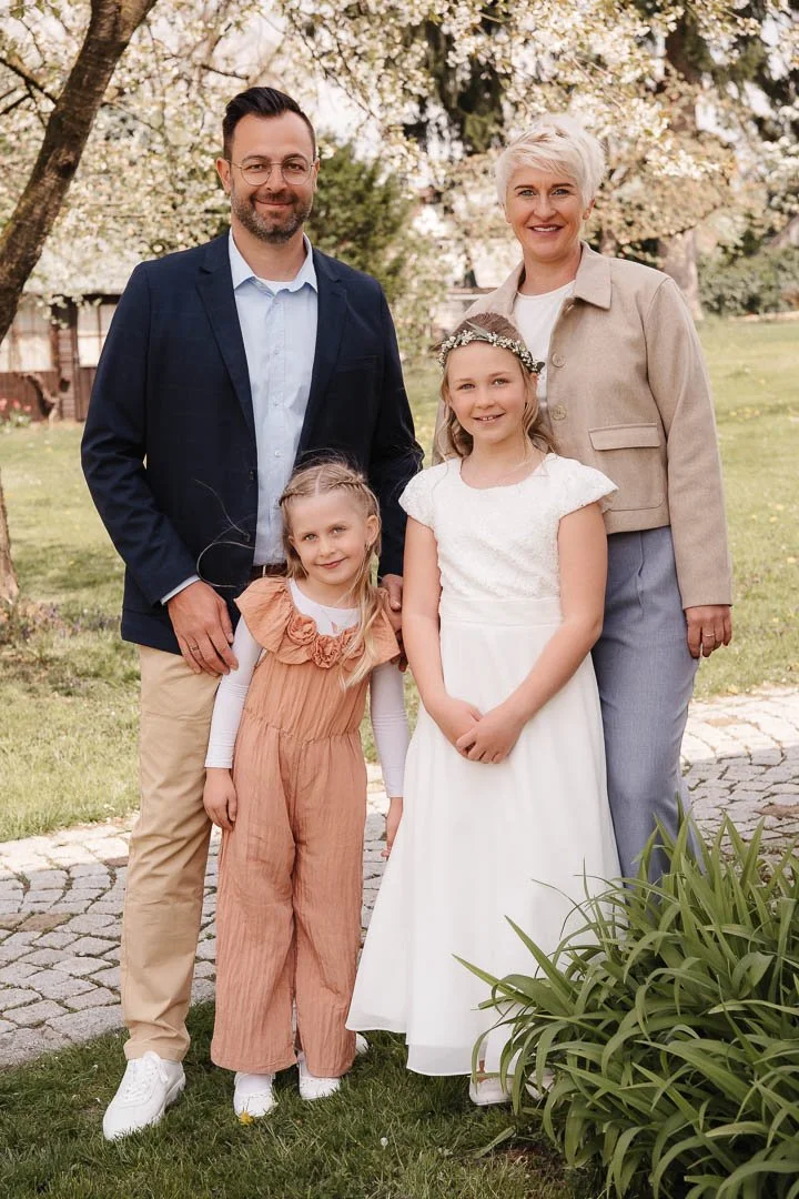 Familienfoto in einem blühenden Garten im Landkreis Günzburg, das eine Familie mit zwei Töchtern in schicker Kommunions-Kleidung zeigt