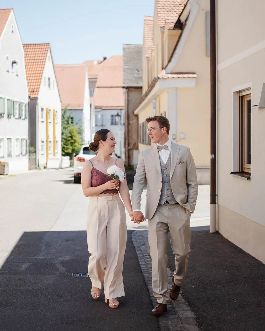 natürliches Hochzeitsfoto in der Altstadt von Friedberg, bei dem ein Hochzeitspaar händehaltend spazieren geht