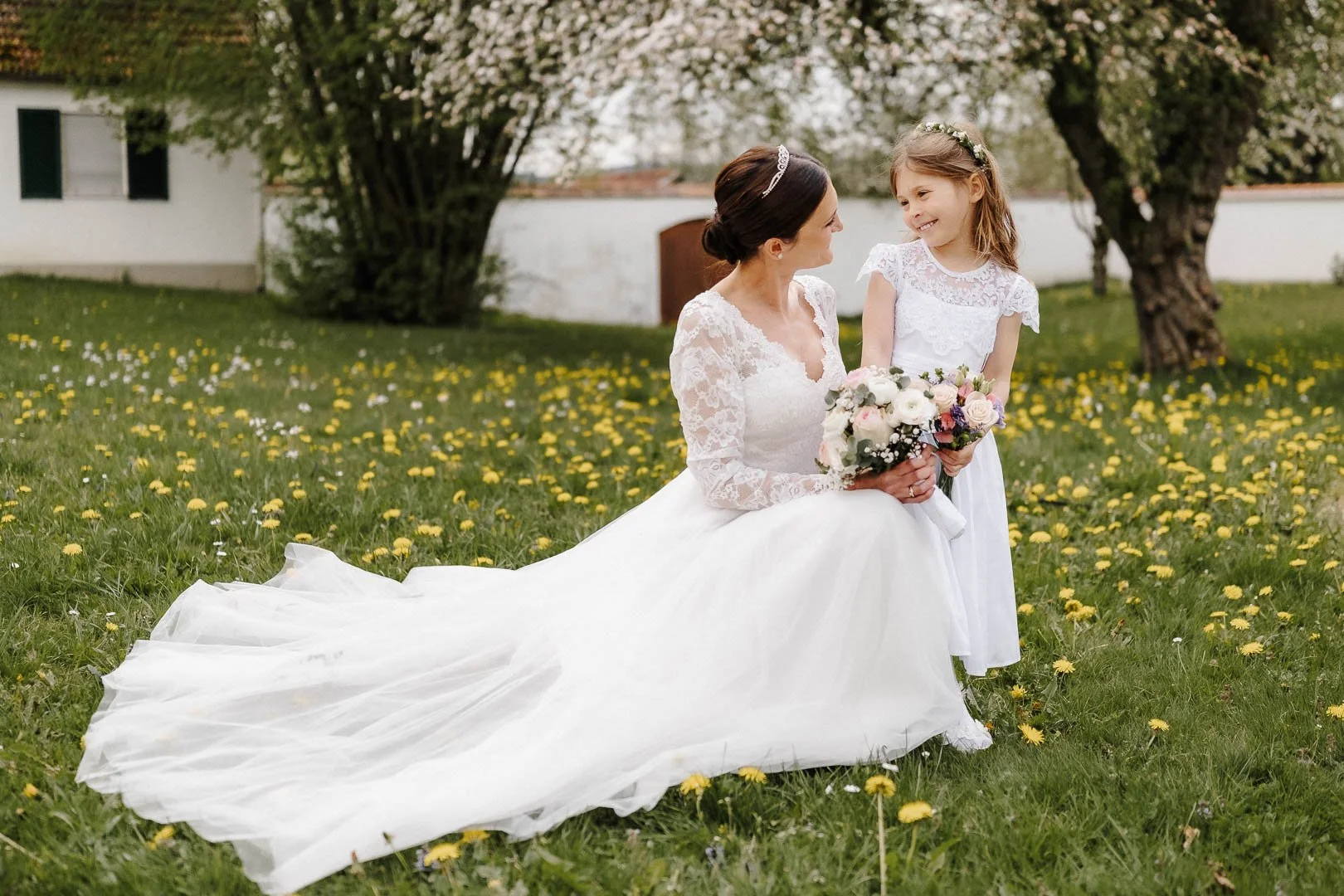Eine Braut und ihre Tochter in weißen Kleidern schauen sich beim Fotoshooting nach der Trauung in der Region Stauden bei Augsburg  emotional und voller Liebe in die Augen