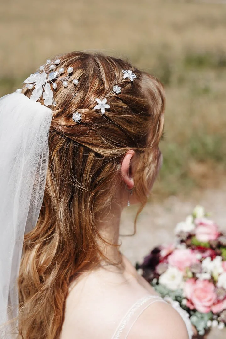 Nahaufnahme der Frisur einer Braut mit blondem Haar mit Haarschmuck