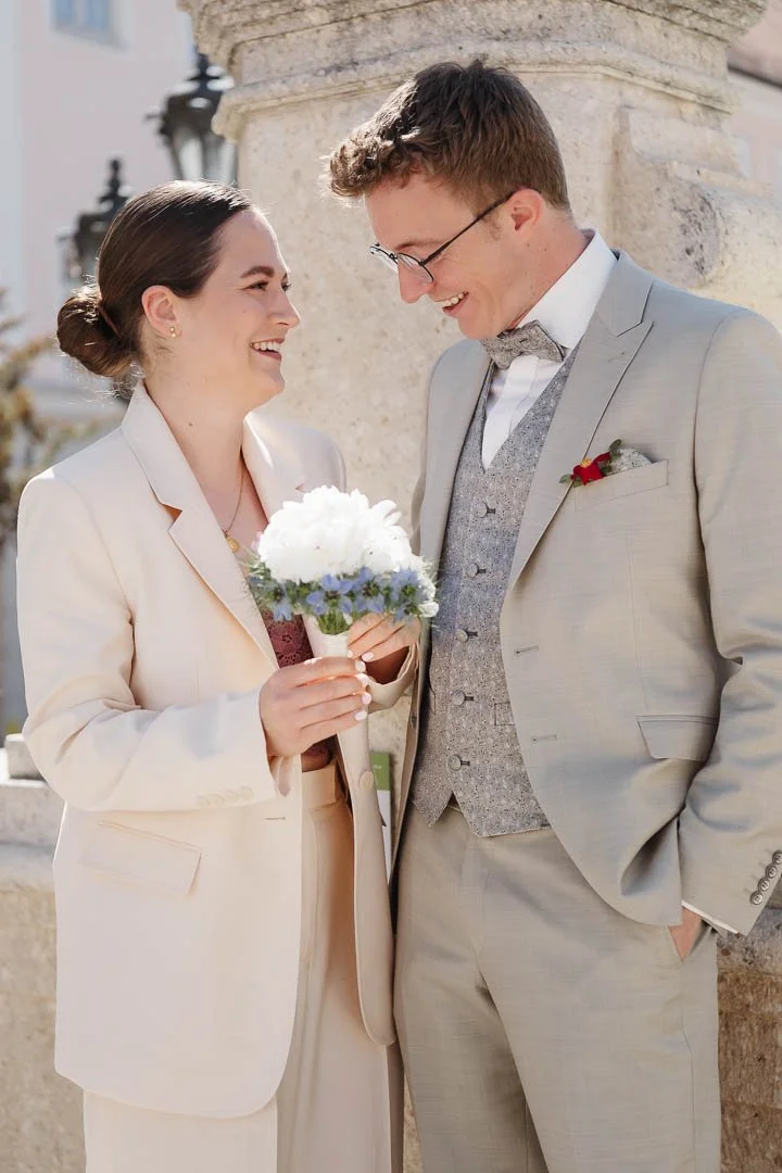 lockeres Foto eines Brautpaares mit Brautstrauß an einem Brunnen direkt nach der Hochzeit in Augsburg