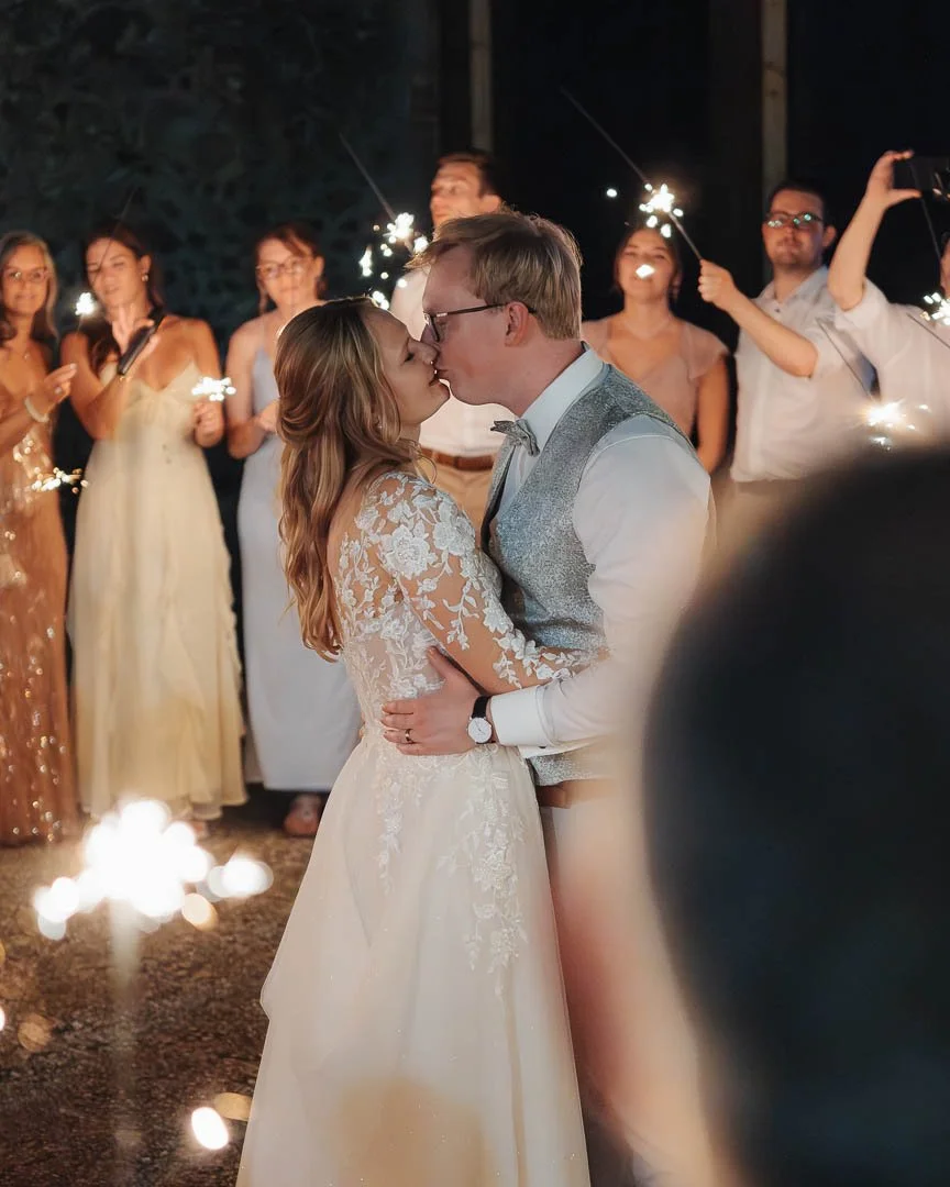 Ein Brautpaar küsst sich beim Hochzeitstanz im Außenbereich einer Hochzeitslocation am Gardasee und ist umgeben von den Hochzeitsgästen, die Wunderkerzen in den Händen halten