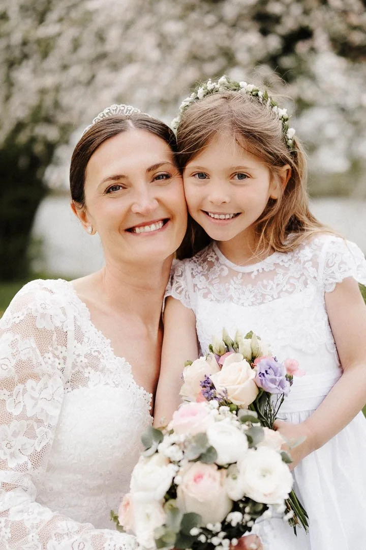 Braut mit ihrer Tochter bei Fotoshooting mit Brautstrauß hinter dem Schloss Elmischwang