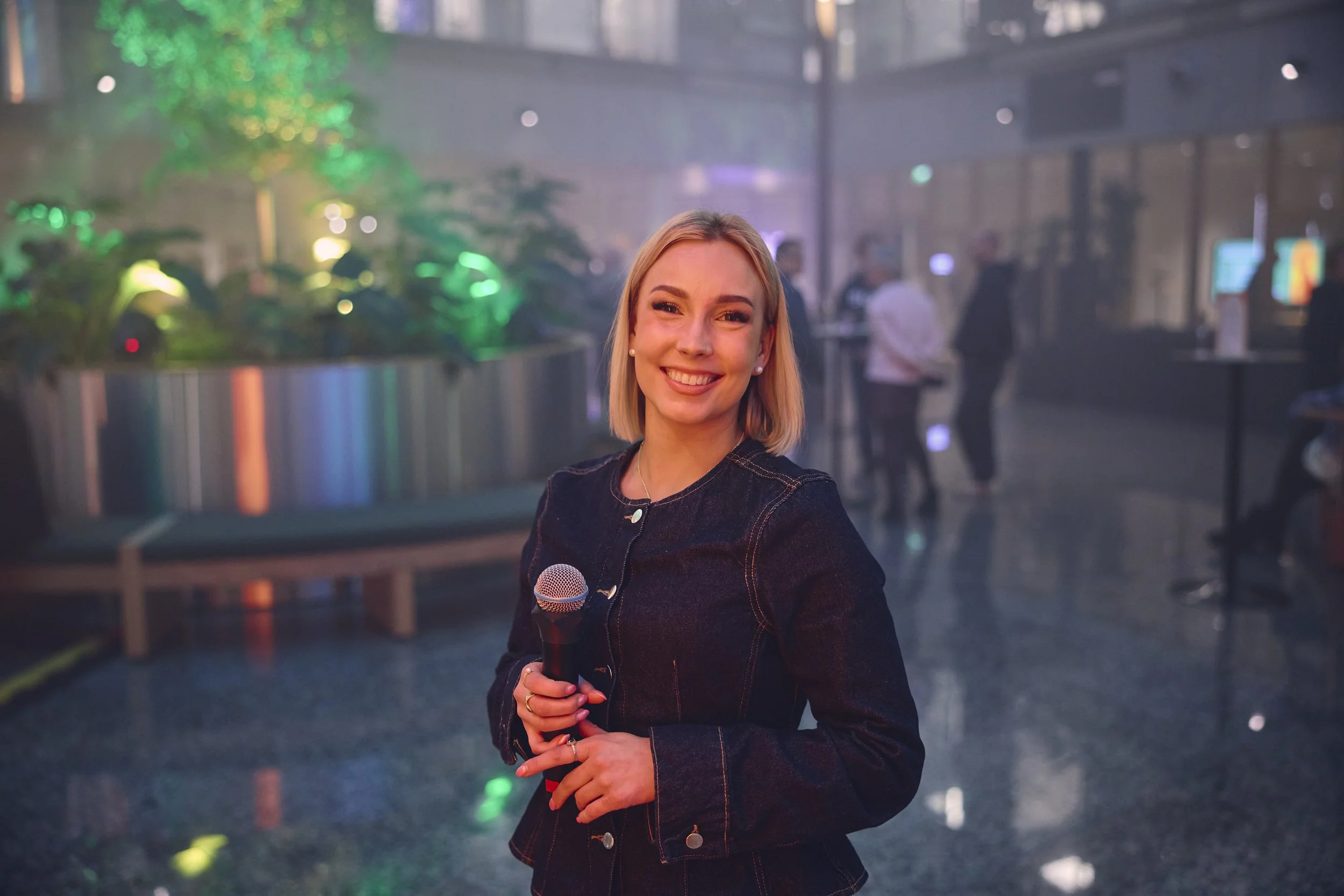 Katariina Kinnunen mikrofoni kädessä rakennuksen aulassa.