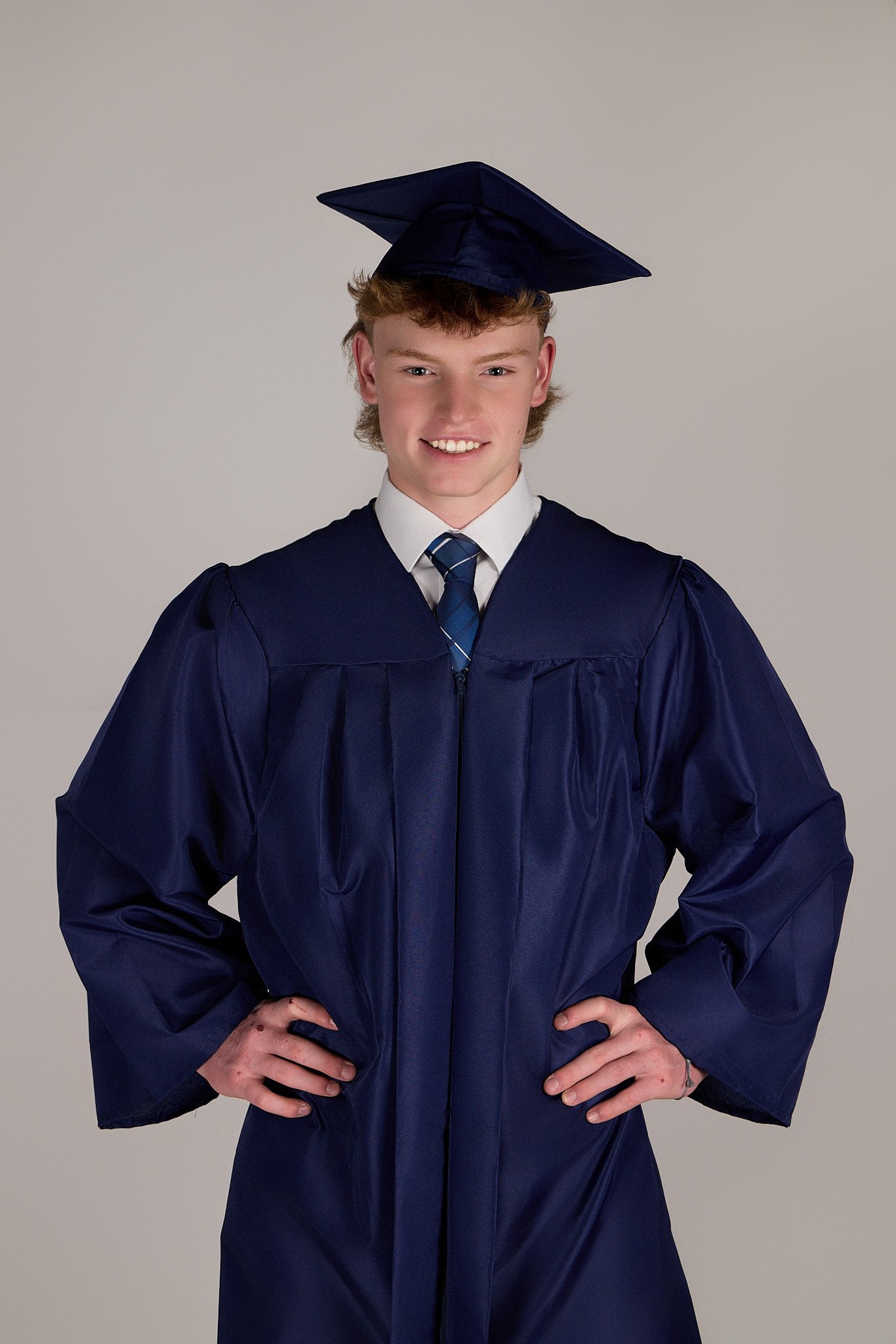 Senior Picture - Young man in graduation cap and gown posing with hands on hips