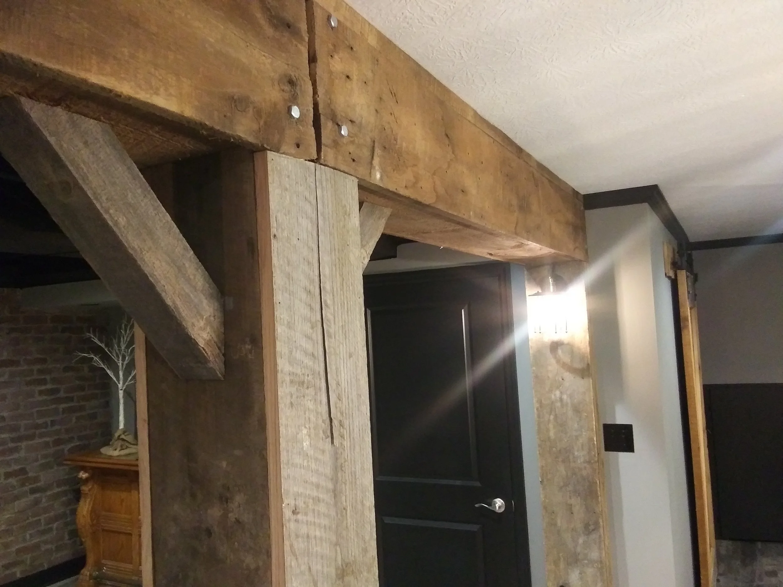 Wooden construction beams in a room with visible brick wall and ceiling lighting.
