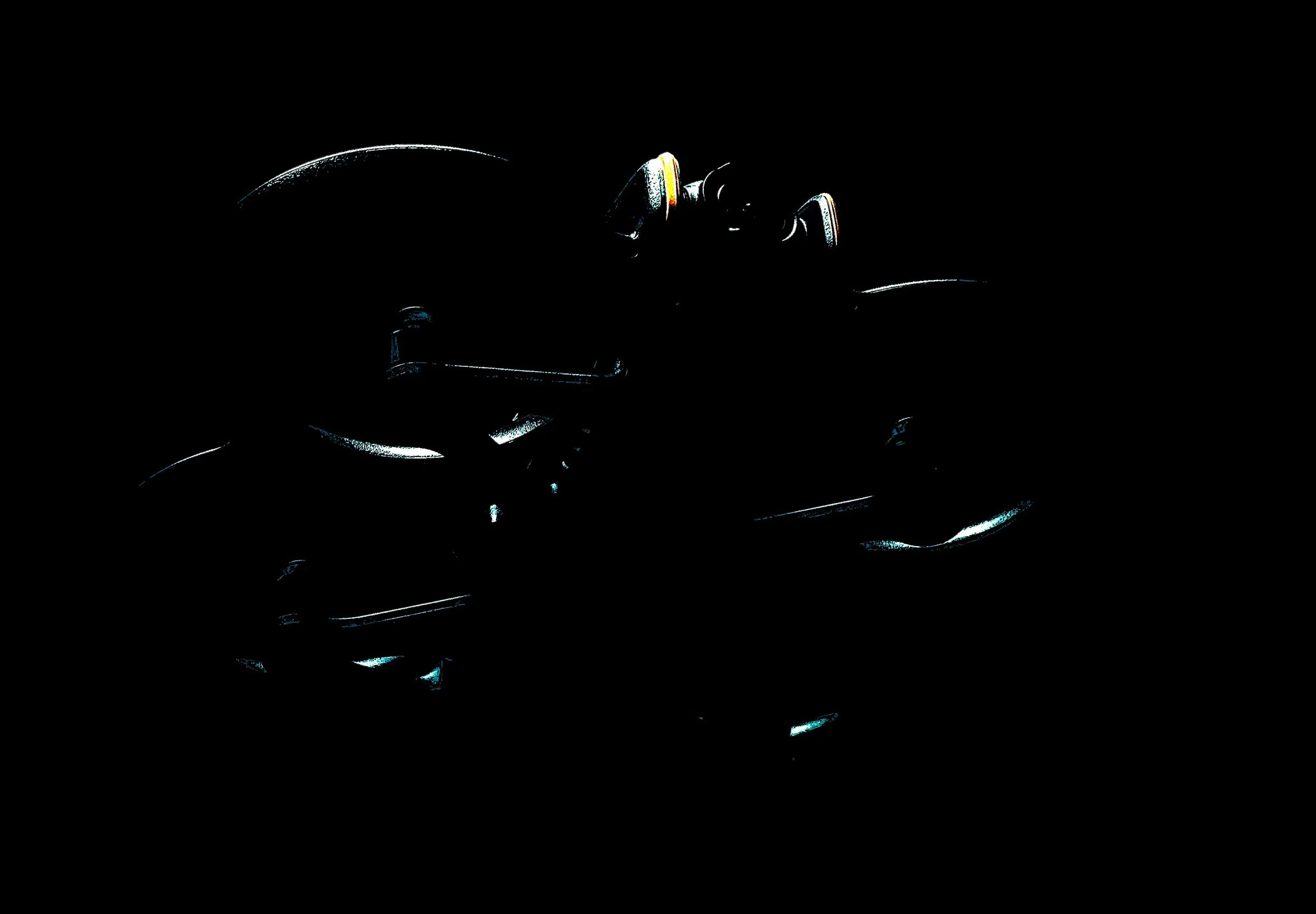 A motorcycle silhouette in darkness with faint reflective highlights on its body.